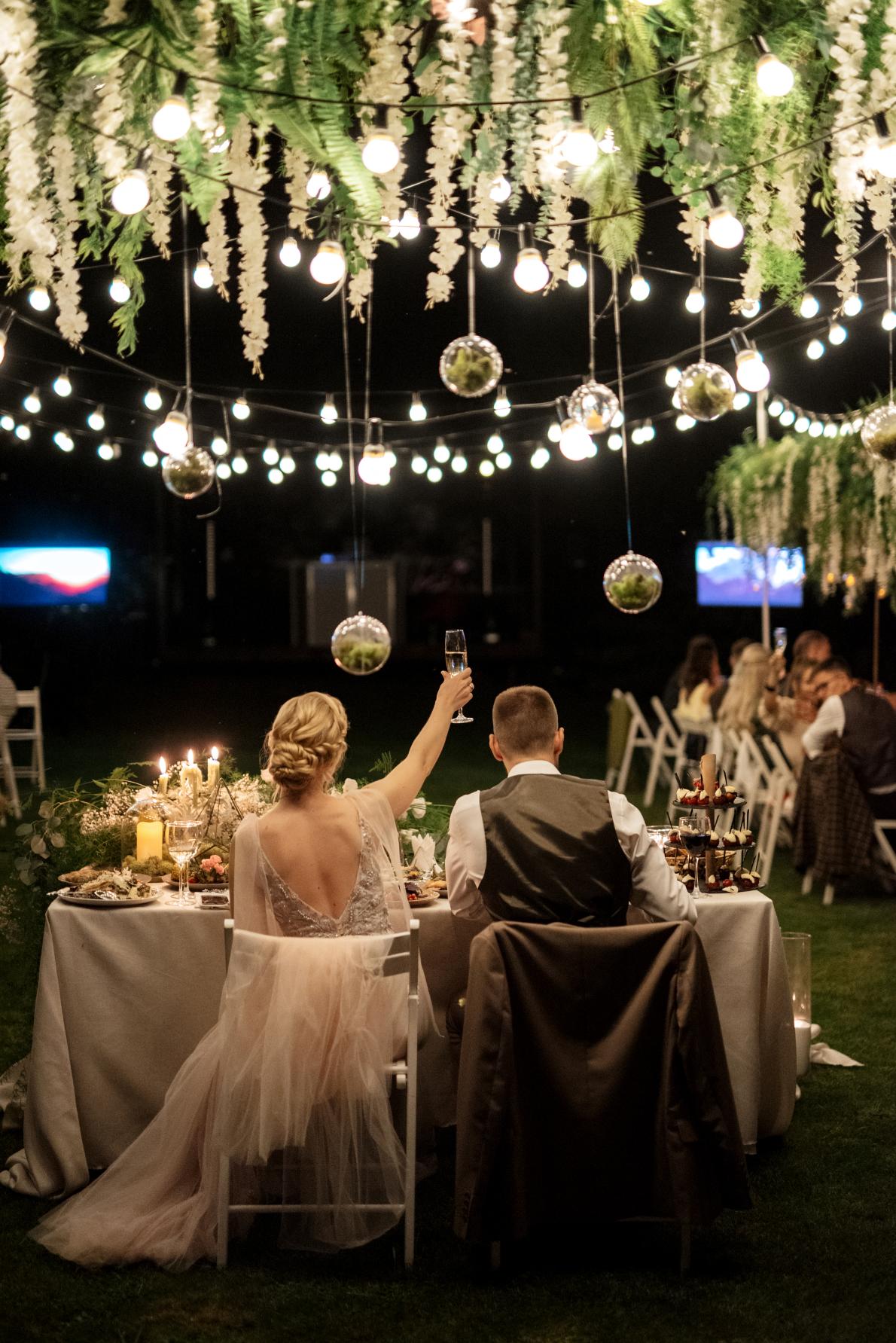 Cena familiar de bodas en el bosque con bombillas y velas